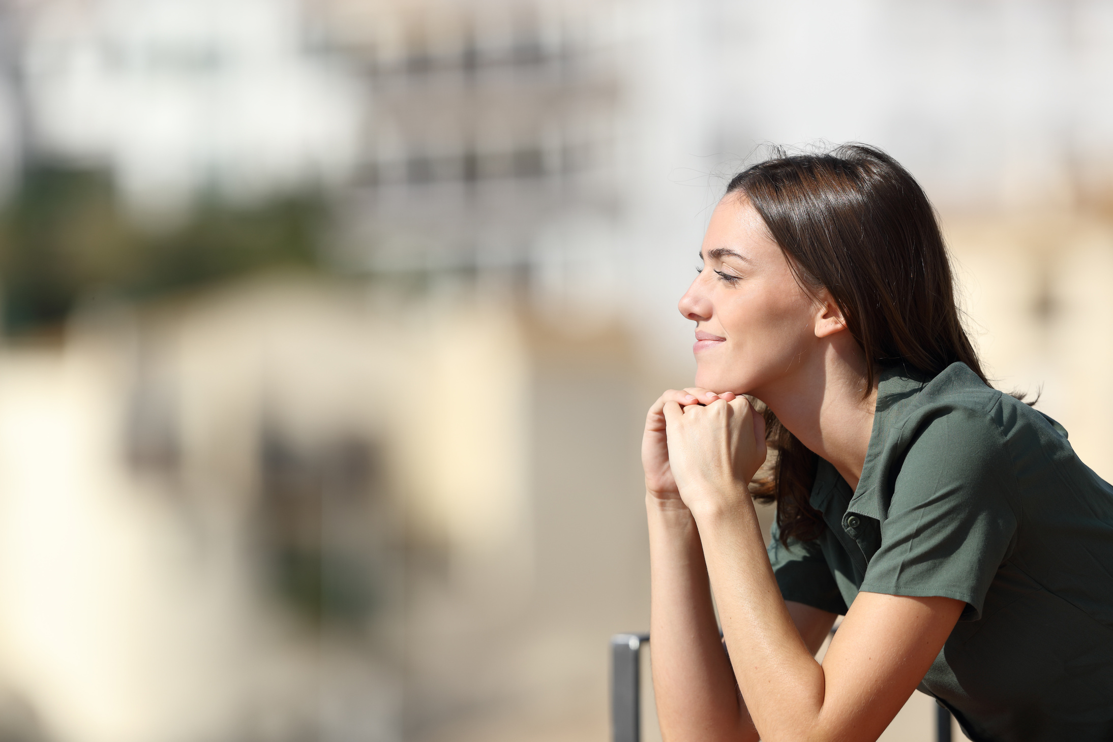 Satisfied woman contemplating from balcony in a town